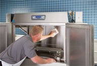 Restaurant employee cleaning a commercial dishwasher